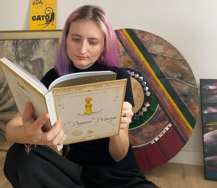 Jaqueline psicóloga lendo o livro O Pequeno Príncipe, em um momento de reflexão e busca por autoconhecimento.