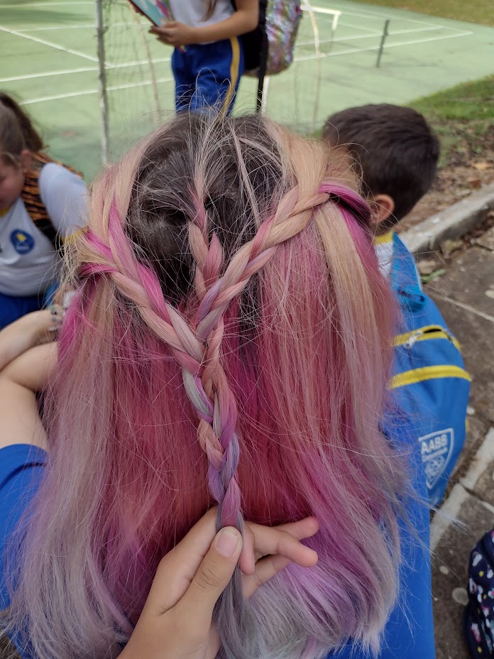 Cabelo colorido sendo trançado em formato de coração, simbolizando o afeto, o cuidado e o vínculo na psicoterapia.
